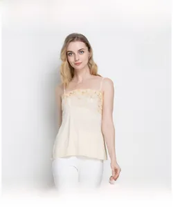 Detailed close-up of beige knitted silk camisole with delicate yellow lace embroidery