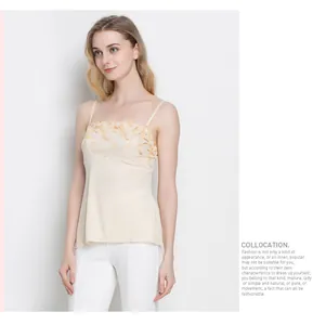 Detail of silk camisole with golden floral embroidery and knit texture on beige fabric