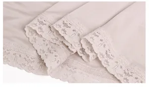Detailed close-up of delicate floral lace trim on soft champagne silk camisole vest