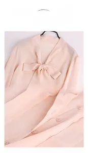 Detailed close-up of pink silk shirt with elegant bow tie neckline and buttons
