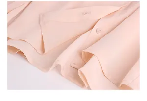 Detailed close-up of light pink silk blouse with refined collar and button stitching
