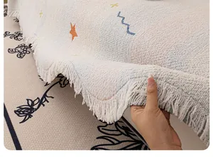 Dettaglio coperta in maglia crema con stelle arancioni e frange morbide sui bordi