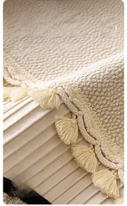 Detail of chenille sofa cover showing elegant pleated hem and tassel fringe decoration