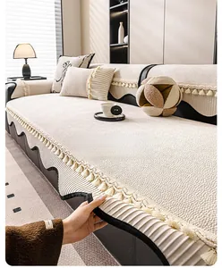 Detail of beige textured chenille sofa cover with decorative fringe and tassel accents