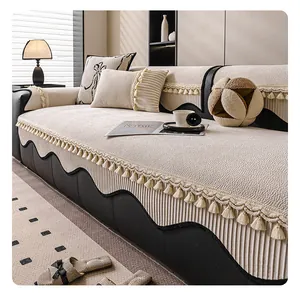 Close-up of cream textured sofa cover with decorative tassels and non-slip embossed pattern