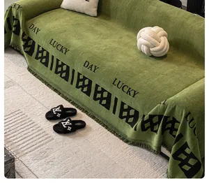 Détail de la housse de canapé en chenille verte avec texte Lucky Day et franges