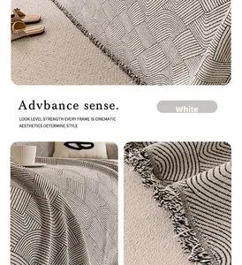 Detail of white chenille sofa cover with wavy geometric patterns and tassel edges