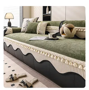 Detailed close-up of dark green velvet sofa cushion with cream tassels and fringe