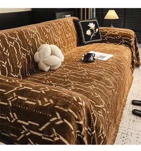 Dettaglio del copridivano morbido con motivo jacquard geometrico e finitura con frange