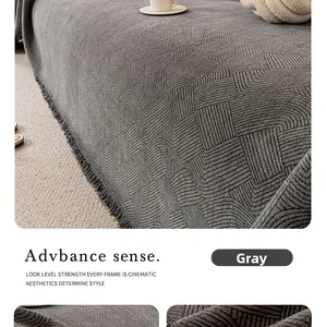 Close-up of gray chenille sofa cover with geometric jacquard texture and elegant tassels