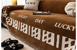 Détail de la housse de canapé en chenille marron avec texte Lucky Day et franges