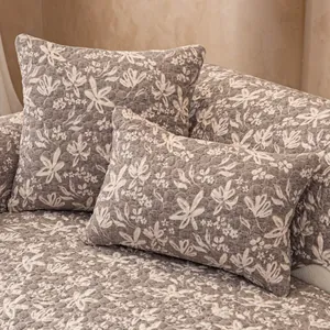 Gesteppter Sofabezug mit Blumenmuster und Kissen in warmen Kaffeebrauntönen