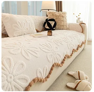 Detail of cream floral embossed sofa cushion with soft texture and decorative brown pom-poms