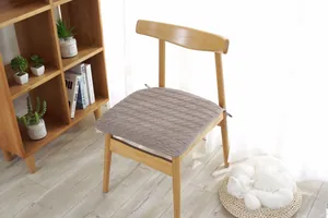 Detalle de cojín de algodón acolchado marrón con diseño de rombos y lazos laterales