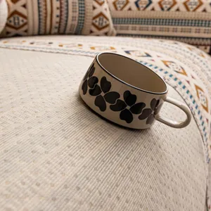 Bohemian chenille sofa cushion with vintage floral ceramic mug on ethnic fabric surface