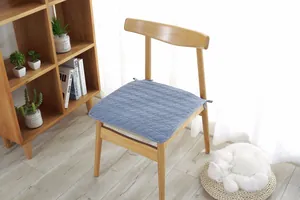 Detalle de cojín de algodón acolchado azul con lazos para silla de madera en oficina