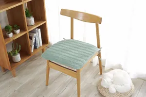Detalle de cojín verde claro en forma de herradura con diseño acolchado y cintas para silla