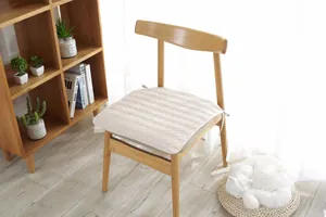 Detalle de cojín acolchado beige para silla con lazos en una silla de madera