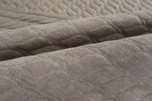 Primer plano del tapete acolchado de algodón marrón con patrones de hojas y textura suave
