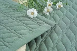 Macro view of sage green quilted cotton mat with non-slip silicone backing and leaf pattern