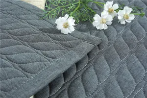 Close-up of dark grey quilted cotton mat with wave pattern stitching and soft texture