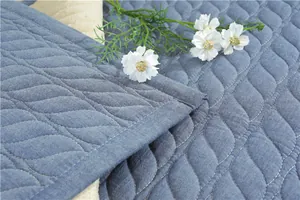 Detail of blue quilted cotton mat showing wave stitching and soft texture