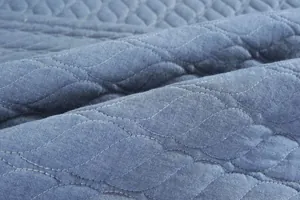 Detalle de cojín para silla de algodón azul con costuras onduladas y textura gruesa