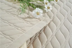 Close-up of beige quilted cotton mat featuring wavy stitching and soft fabric texture