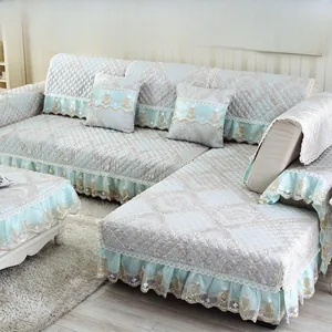 Detail of light blue floral jacquard sofa cover with white lace trim and tassel fringe