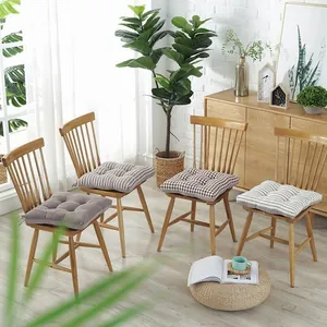 Detail of thickened linen cushions with button tufting and ties on wooden chairs