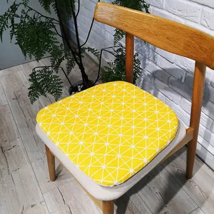 Detail of yellow linen seat cushion with white geometric pattern on a wooden chair
