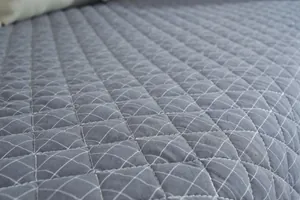 Macro detail of grey quilted cotton chair pad featuring classic diamond stitching pattern