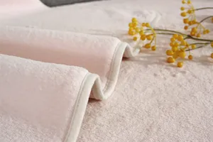 Gros plan sur la texture épaisse du tapis en peluche rose avec finition de bordure soignée