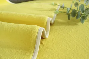 Gros plan du tapis en fausse fourrure jaune vif avec bordure crème et finitions soignées
