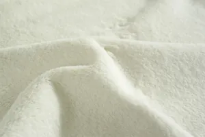 Gros plan d'un tissu épais en fausse fourrure de lapin blanc crème au toucher doux