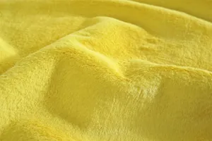 Détail macro du tissu en fausse fourrure jaune vif avec une texture douce et dense soyeuse