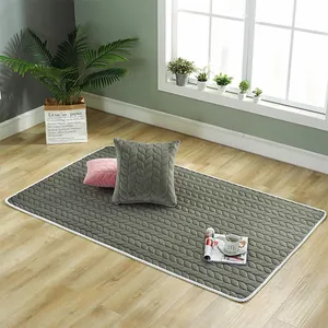 Detail of grey quilted plush rug and pillows showing leaf patterns on wooden floor