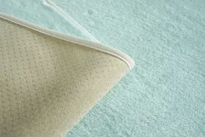 Détail du coussin en peluche bleu clair avec base antidérapante et bords blancs impeccables