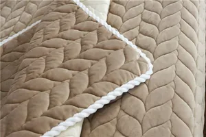Macro detail of plush taupe sofa mat featuring leaf-pattern quilting and corded piping