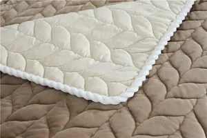 Detailed leaf-patterned quilted fabric showing khaki velvet surface and white piping edge