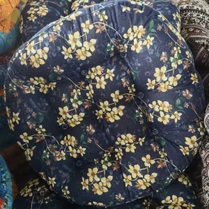 Close-up of a blue round floor cushion featuring yellow floral patterns and tufted buttons