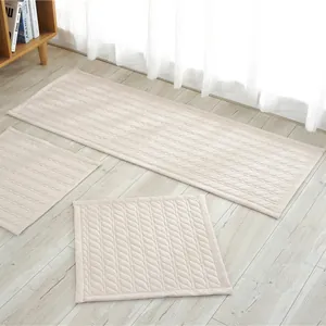 Detalle de cojines acolchados de algodón beige con textura de ondas sobre madera