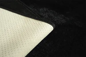 Gros plan d'un tapis en peluche noire avec envers antidérapant et bordure cousue