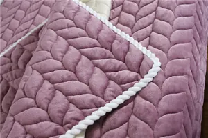 Detail of purple plush quilted fabric with leaf pattern and white rope braided edge
