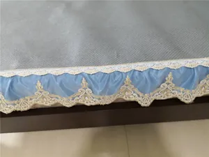 Close-up of European style bed skirt with gold lace embroidery and blue pleated satin edge