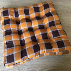 Detail of square cotton linen chair cushion with orange plaid pattern and tufted design