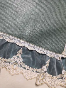 Detailed close-up of dark green woven mat with elegant floral lace and golden embroidery