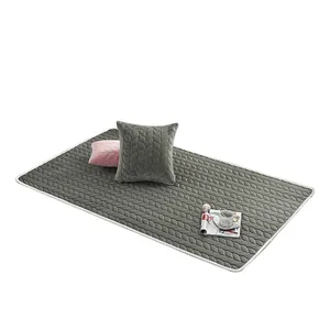 Grey quilted plush rug with leaf pattern texture and decorative throw pillows