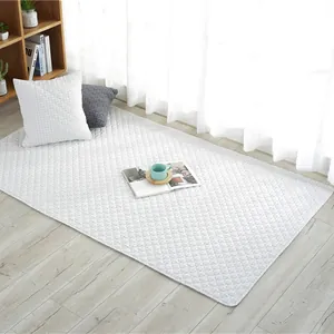 White quilted cotton baby crawl mat featuring a classic diamond pattern on light wood floor