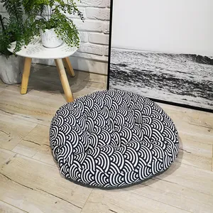 Detail of round Japanese floor cushion with black and white wave pattern on wood floor